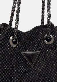 Borsa a tracolla nera con manici intrecciati, occhielli in metallo e una placca logo triangolare. Presenta una superficie testurizzata con perline riflettenti.