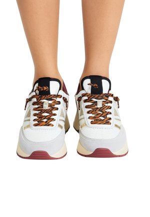 Sneakers bianche con lacci a fantasia arancione e nera, dettagli grigi e strisce riflettenti; presentano un colletto imbottito e suole in gomma.