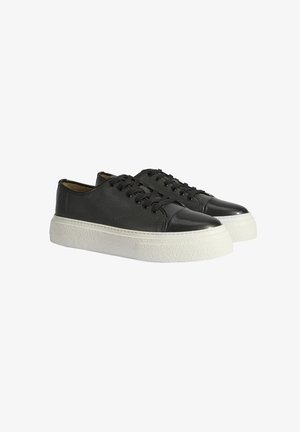 Zwarte leren sneakers met een gestructureerde afwerking, glanzende zwarte neuzen en witte rubberen zolen. Voorzien van platte veters en een strak ontwerp.