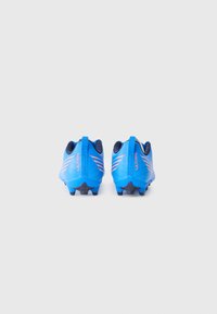 Botas de fútbol azules con un upper texturizado, que presentan acentos naranjas, una pestaña en el talón y tachones negros en una suela flexible. Adecuadas para césped artificial.
