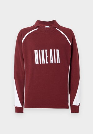 Bordová košile s dlouhým rukávem a bílým límečkem a bílými akcenty. Na hrudi je velkými bílými písmeny vytištěn nápis "NIKE AIR".