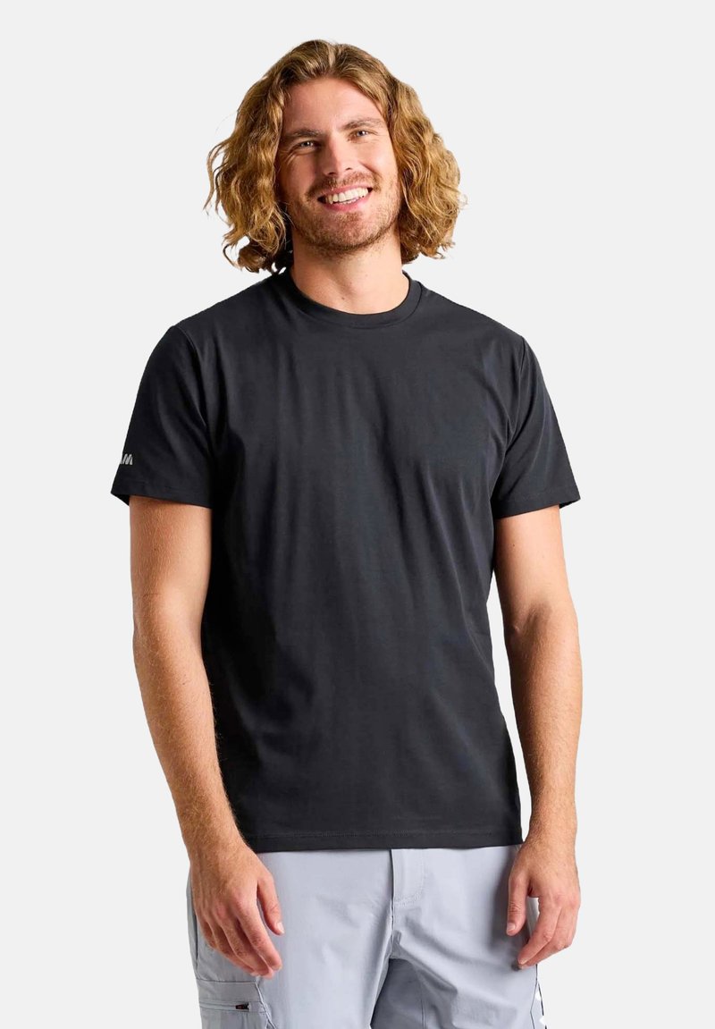 T-shirt in cotone nero con maniche corte, scollatura a girocollo e un logo discreto sulla manica sinistra. Texture liscia. Il modello è posizionato su uno sfondo chiaro.