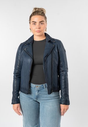 Veste de moto en cuir bleu foncé avec fermeture éclair, revers inclinés, et coupe ajustée. Portée avec un haut noir et un jean délavé clair.