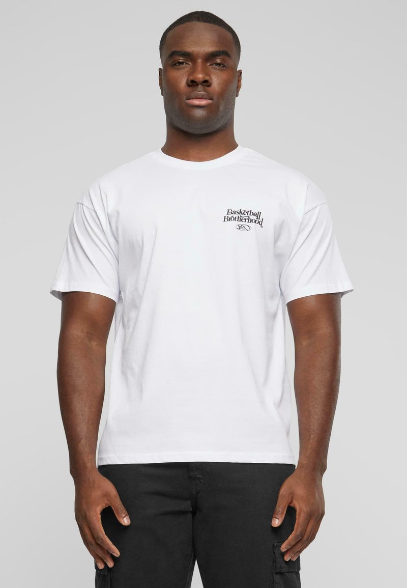 Hvid bomulds t-shirt med korte ærmer, der har sort "Basketball Brotherhood" tekst på venstre brystområde. Standard pasform, minimalistisk design.