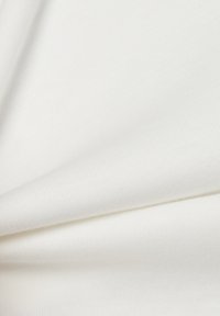 White cotton fabric with a soft texture, displaying a slight stretch and a smooth finish, folded to show its even, consistent surface.