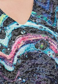 Tričko s výstřihem do V s černým podkladem, které má barevný abstraktní design v růžové, modré a zelené barvě, zdobené malými modrými a metalickými hroty.