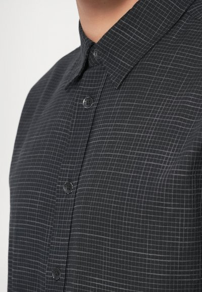 Sort skjorte med knapper, der har et gittermønster, klassisk krave og tekstureret stof med kontrasterende hvide linjer. Knapperne er runde og mørke.