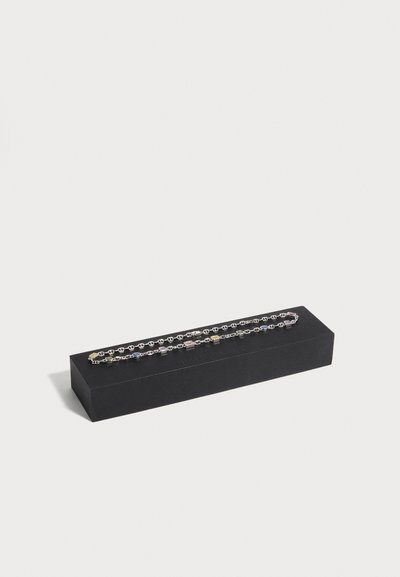 Bracelet chaîne en argent avec pierres précieuses multicolores carrées et ovales présenté sur une boîte rectangulaire noire sur fond blanc.