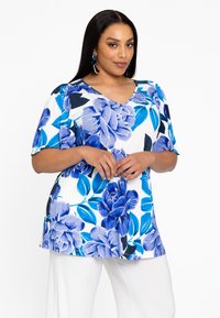 Bloemrijke tuniektop met korte mouwen. Kenmerkt zich door een blauw bloemenpatroon op een witte achtergrond en een V-halslijn. Zachte stof met een comfortabele pasvorm.