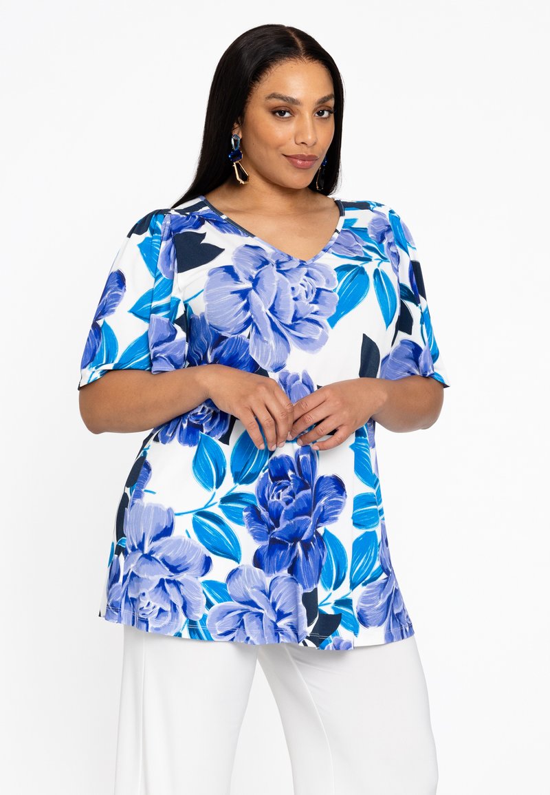Bloemrijke tuniektop met korte mouwen. Kenmerkt zich door een blauw bloemenpatroon op een witte achtergrond en een V-halslijn. Zachte stof met een comfortabele pasvorm.