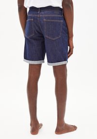 Shorts in denim scuro, con risvoltini, cinque tasche e dettagli cuciti. I pantaloni hanno una vestibilità dritta e un'etichetta in vita.