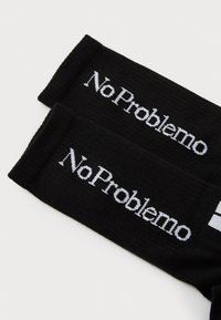 Calcetines negros con el texto blanco "No Problemo" bordado en el puño, que presentan una textura acanalada y un diseño sencillo.