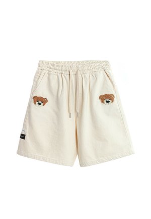 Pantalones cortos de color crema con cintura elástica y cordón, con caras de osito de peluche marrón bordadas sobre cada bolsillo delantero.