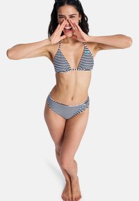 Bikini à rayures noires et blanches avec un haut triangulaire et un bas taille haute. Présente un petit logo sur le haut. Tissu lisse et matériel minimal.