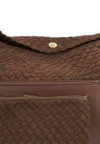 Brown woven fabric handbag with a textured surface, featuring a gold snap closure and a front zippered pocket with gold hardware accents.
