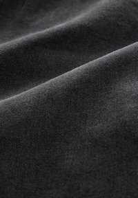 Tissu noir doux avec une texture fine tricotée et des plis subtils créant des ombres douces et de la profondeur.
