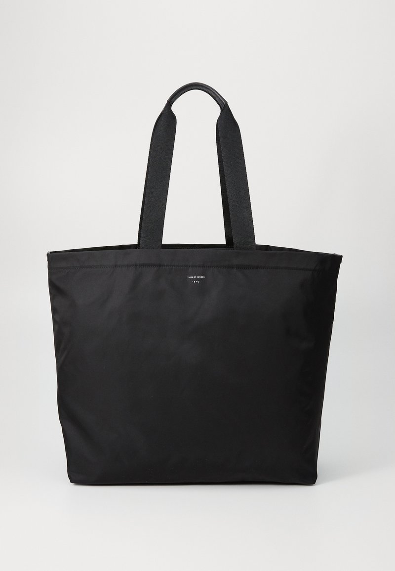 Μαύρη τσάντα tote κατασκευασμένη από ανθεκτικό ύφασμα, με δύο ανθεκτικές λαβές και απλό σχέδιο με υφή στην επιφάνεια και ελάχιστη σήμανση.