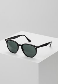 Sorte solbriller med grønne linser, firkantet stel, glansfuld overflade, sølv hardware detaljer og et distinkt Ray-Ban logo på siden.