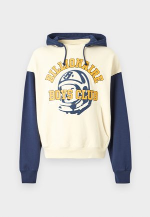 Huppari kermansävyinen, laivastonsinisillä hihoilla. Edessä suuri keltainen teksti "BILLIONAIRE BOYS CLUB" ja sininen graafinen kuvio.