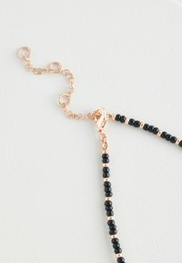 Black beaded necklace with alternating rose gold accents, featuring a lobster clasp and adjustable chain for length customization.