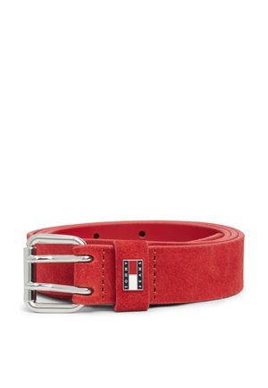 Rode suède riem met zilveren dubbele gesp en klein Tommy Jeans-logo op de riemlus, opgerold op een witte achtergrond.