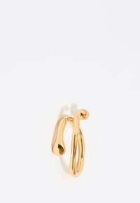 Pendiente de metal en tono dorado con un diseño retorcido y fluido, de superficie lisa y bordes redondeados, que refleja la luz con un acabado pulido.