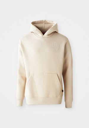 Beige pulóver kapucnival, elülső zsebbel, húzózsinóros kapucnival és fényes "ALPHA INDUSTRIES" logóval a bal mellrészen. Puha szövettextúra.