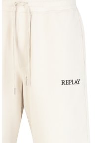 Crème-kleurige sweatpants met verstelbare trekkoord in de taille, zijzakken en zwart geborduurd "REPLAY" logo op de linkerdij.