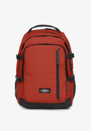 Červený nylonový batoh s černými akcenty, několika zipovými přihrádkami, polstrovanými popruhy a horním madlem pro snadné nošení.