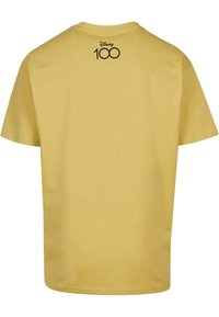 Gul bomull T-skjorte med korte ermer. Har rund hals og en svart "Disney 100" logo trykt på ryggen.