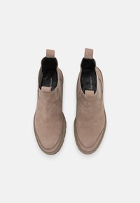 Stivali alla caviglia in suede beige chiaro con pannelli elastici laterali. Punta arrotondata e suola testurizzata a contrasto. Anello sul tallone per una facile calzata.