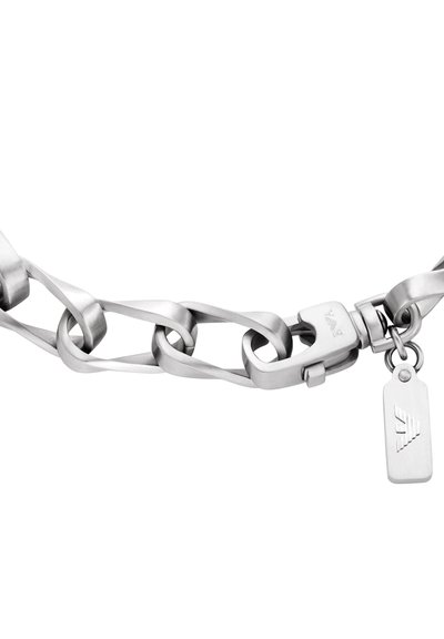 Bracelet chaîne en acier inoxydable avec maillons entrelacés, équipé d'un fermoir et d'une petite étiquette avec un logo. Texture lisse et polie.