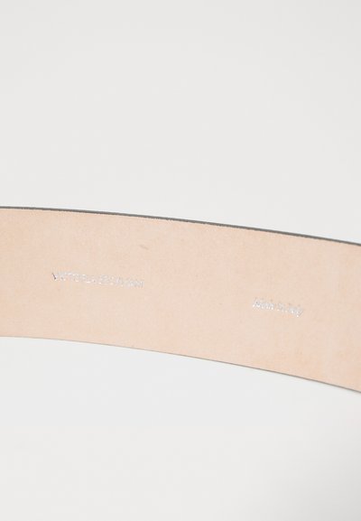 Tan leather belt featuring a smooth surface, curved shape, and silver embossed branding reading "Victoria Beckham" and "Made in Italy."
