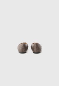 Brown patterned flats with a rounded toe, flat sole, and small decorative accents at the back. Made from textured synthetic material.