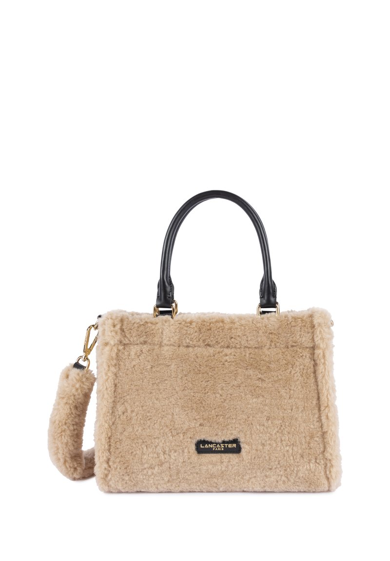 Borsa fluffy beige con manici in pelle nera e accenti in metallo dorato. Forma rettangolare con una texture morbida e un'etichetta con il logo del marchio.