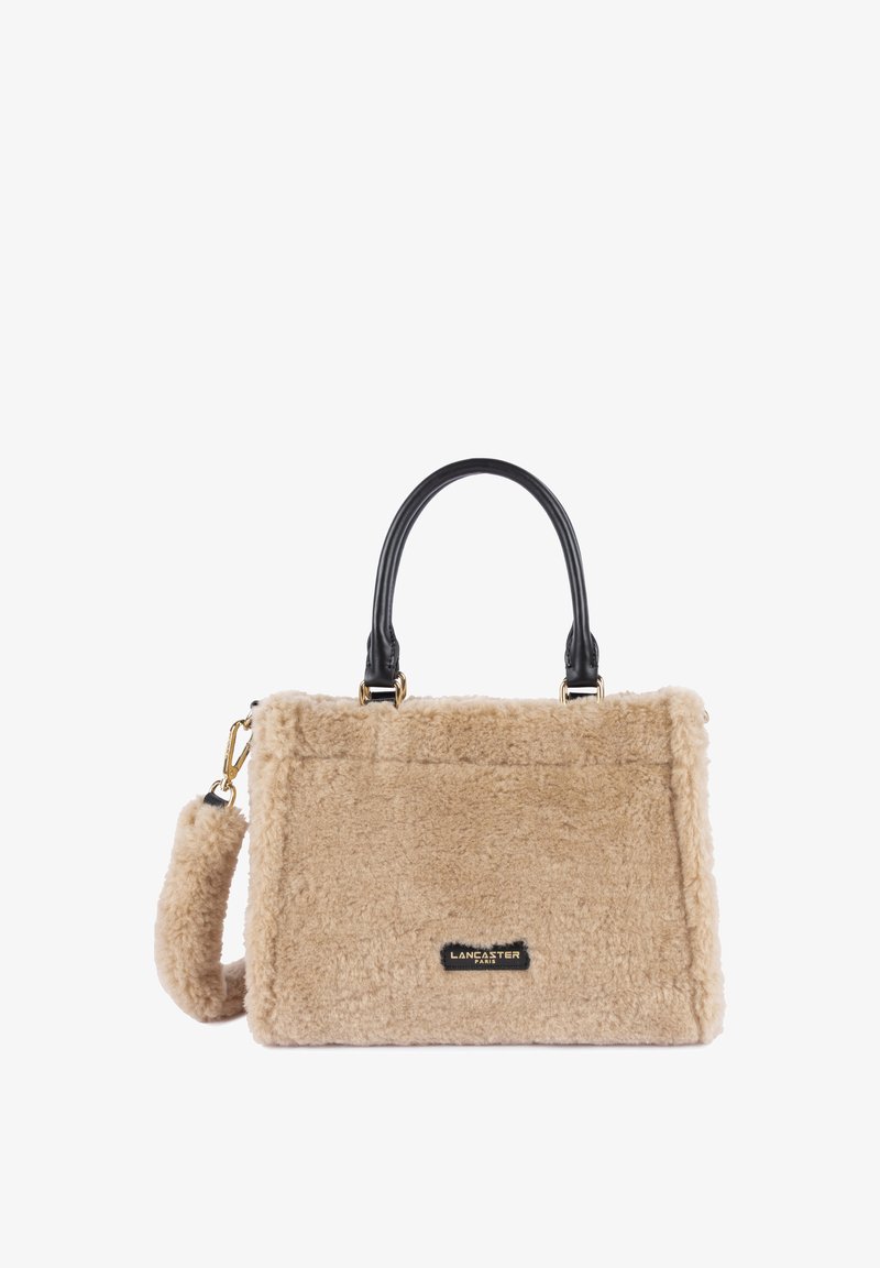 Borsa fluffy beige con manici in pelle nera e accenti in metallo dorato. Forma rettangolare con una texture morbida e un'etichetta con il logo del marchio.