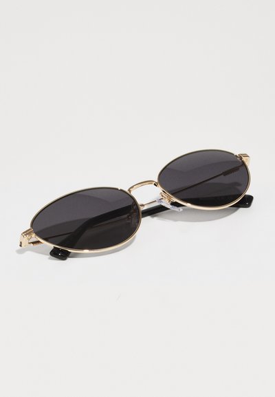 Gold metal sunglasses with oval dark lenses, featuring a thin frame and black temple tips. Distinctive double bridge design.