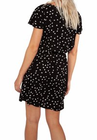 Robe noire avec un imprimé floral blanc, manches courtes, taille ajustée et coupe décontractée. Tissu doux avec un design fluide.