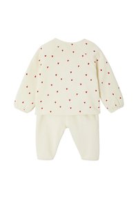 Cremfarbene Babybekleidung mit langen Ärmeln, Hose und kleinen roten Herzmustern, die über das Oberteil und die Ärmel verteilt sind.