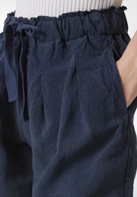 Námořnické modré, lehkékalhoty z tkaniny s elastickým pasem, šňůrkou a bočními kapsami. Mají měkkou texturu a uvolněný střih.