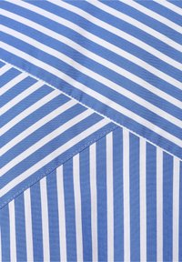 Blau-weiß gestreifter Stoff mit diagonalen und vertikalen Nählinien, die ein Muster aus unterschiedlich ausgerichteten Streifen erzeugen.