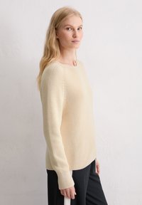 Crèmekleurige, gestructureerde gebreide sweater met lange mouwen, ronde halslijn en ribgebreide accenten bij de mouwen en de zoom. Eenvoudig, modern ontwerp.