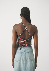 Top corto multicolore con design incrociato, caratterizzato da fantasie grafiche, spalline regolabili e un dettaglio annodato sul retro.