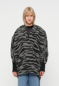 Manteau enveloppant oversize à motif zèbre en tissu texturé gris et noir, avec de larges manches et un col châle.