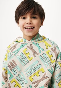 Mikina s kapucí vyrobená z béžové látky s hravým vícebarevným textem v světle modré, žluté, hnědé a zelené. Vzor textu je geometrický.