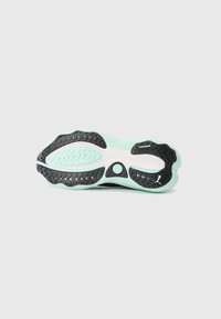 Semelle d'une chaussure de course Puma noire et vert menthe avec une texture antidérapante, logo Puma et système d'amorti visible.