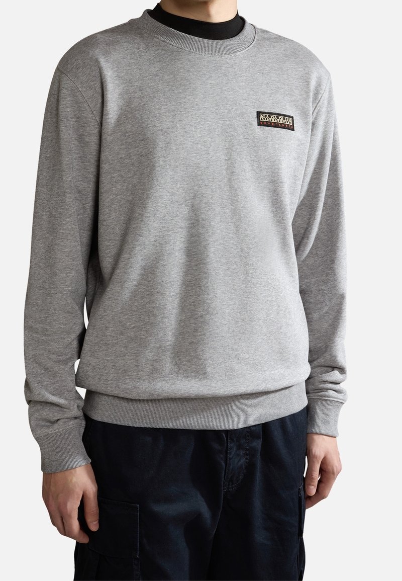 Sweat-shirt gris en tissu doux, avec col rond, poignets et ourlet côtelés, orné d'un petit patch logo sur la poitrine gauche.