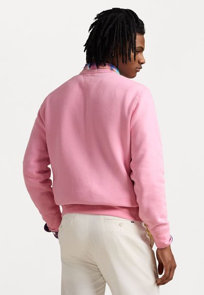 Pink sweatshirt med rund halsudskæring, ribbestrikkede manchetter og kant, kombineret med beige bukser. Glat stof med en afslappet pasform.