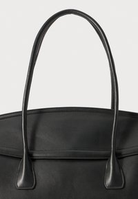 Sac en cuir noir avec deux longues anses, une texture lisse, et un design minimaliste agrémenté d'une couture le long du dessus.