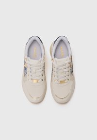 Sneaker beige con tomaia in tessuto testurizzato, dettagli metallici oro e un design floreale blu sui lati. Lacci bianchi e colletto imbottito.